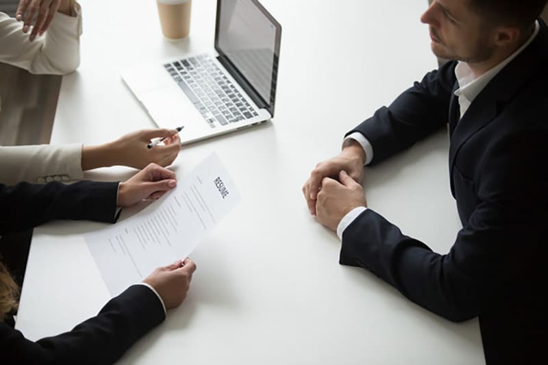 Reclutadora revisando un currículum impreso durante una entrevista