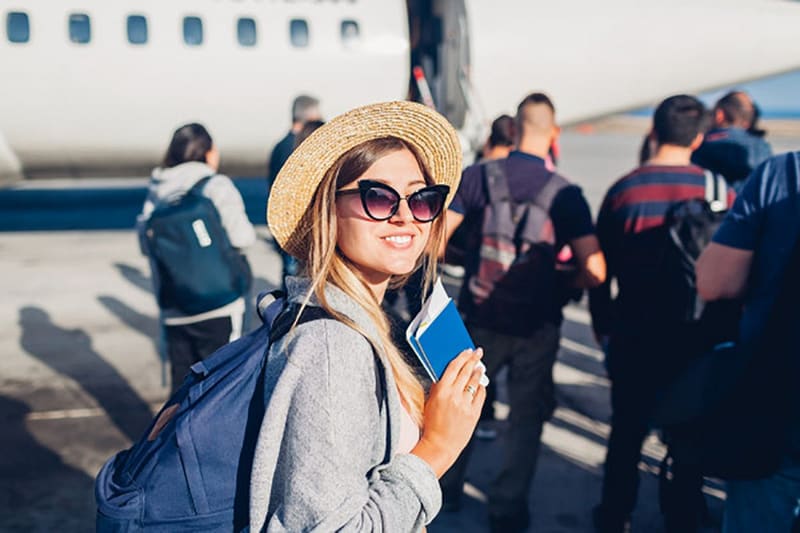 Viajera feliz con pasaporte y mochila lista para abordar un avión