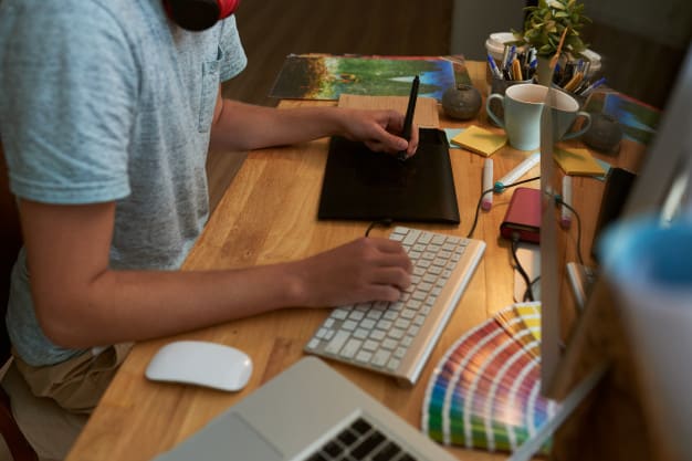 Diseñador freelance trabajando con tableta gráfica y muestrario de colores